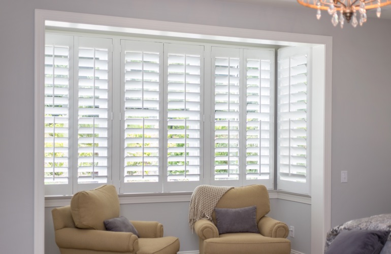 North-South windows can have energy efficiency issues rather than problems with sun glare. White plantation shutters in sitting area